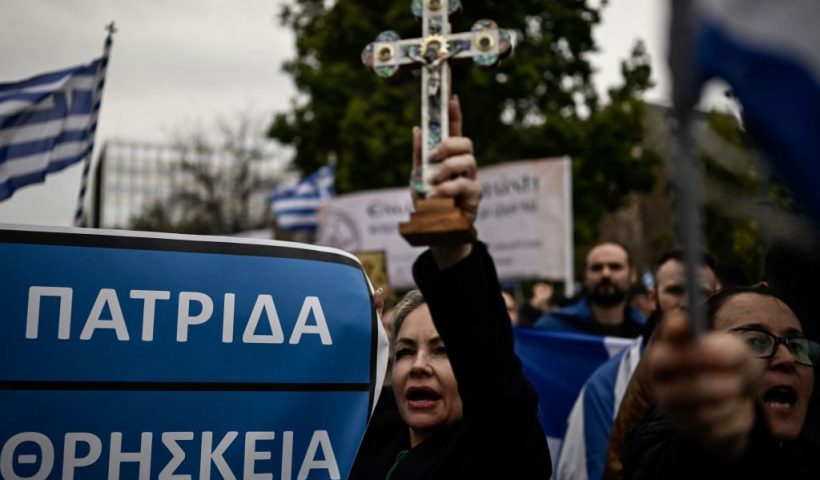 A protester brandishes a cross during a demonstration against a reform legalising same-sex marriage and adoption, that will be debated by parliament next week, in Athens on February 11, 2024. Some 4,000 people according to police responded to a call by Orthodox religious groups. They gathered on central Syntagma Square, waving Greek flags and brandishing crosses and banners opposing same-sex parenthood. (Photo by Aris MESSINIS / AFP) (Photo by ARIS MESSINIS/AFP via Getty Images)