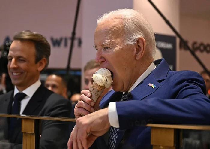 TOPSHOT - US President Joe Biden (R), flanked by host Seth Meyers (L), eats an ice cream cone at Van Leeuwen Ice Cream after taping an episode of "Late Night with Seth Meyers" in New York City on February 26, 2024. (Photo by Jim WATSON / AFP) (Photo by JIM WATSON/AFP via Getty Images)