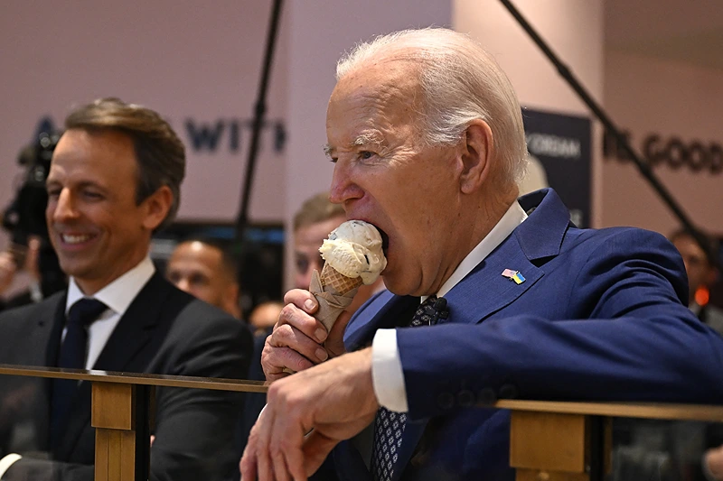 TOPSHOT - US President Joe Biden (R), flanked by host Seth Meyers (L), eats an ice cream cone at Van Leeuwen Ice Cream after taping an episode of "Late Night with Seth Meyers" in New York City on February 26, 2024. (Photo by Jim WATSON / AFP) (Photo by JIM WATSON/AFP via Getty Images)
