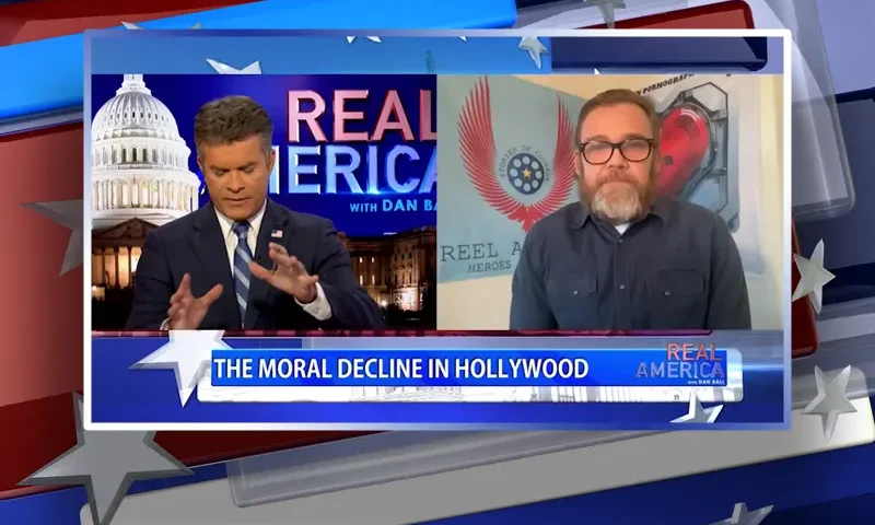 Video still from Real America on One America News Network showing a split screen of the host on the left side, and on the right side is the guest, Ricky Schroder.