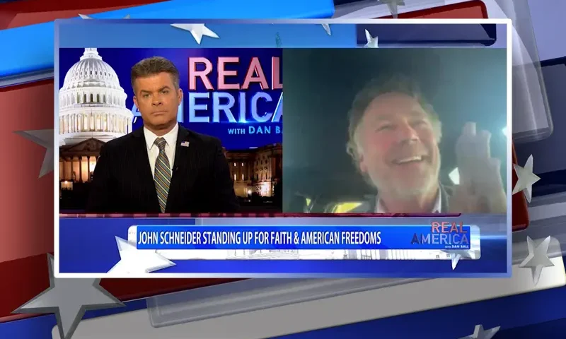 Video still from Real America on One America News Network showing a split screen of the host on the left side, and on the right side is the guest, John Schneider.