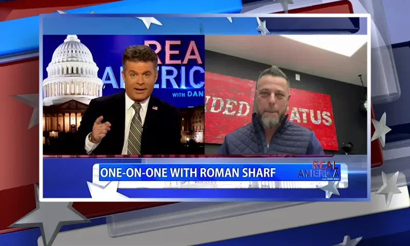 Video still from Real America on One America News Network showing a split screen of the host on the left side, and on the right side is the guest, Roman Sharf.