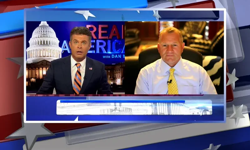 Video still from Real America on One America News Network showing a split screen of the host on the left side, and on the right side is the guest, Rep. Troy Nehls.