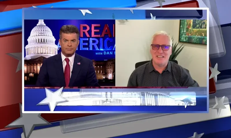 Video still from Real America on One America News Network showing a split screen of the host on the left side, and on the right side is the guest, Jim Hoft.