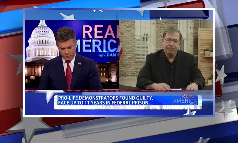 Video still from Real America on One America News Network showing a split screen of the host on the left side, and on the right side is the guest, Father Frank Pavone.
