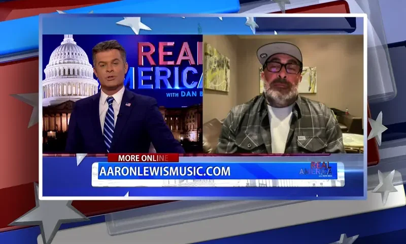 Video still from Real America on One America News Network showing a split screen of the host on the left side, and on the right side is the guest, Aaron Lewis.