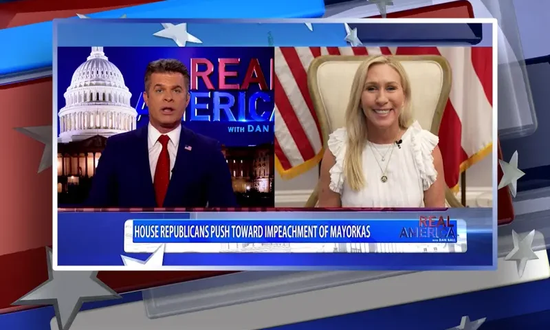 Video still from Real America on One America News Network showing a split screen of the host on the left side, and on the right side is the guest, Rep. Marjorie Taylor Greene.