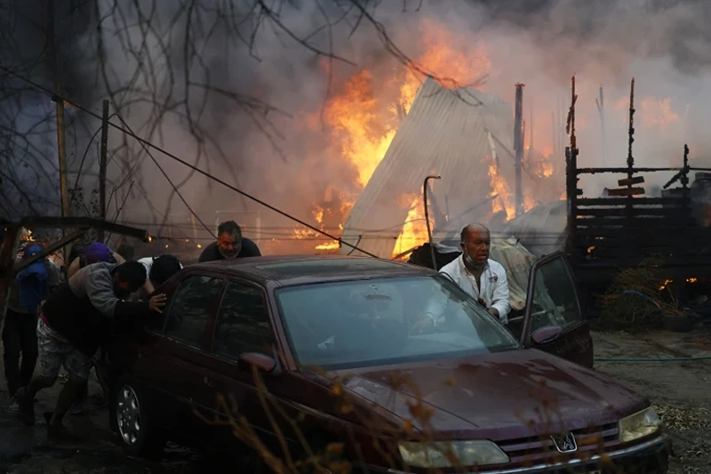 3 of 10 | Residents push a car away from a burning forest fire engulfing homes in Villa Alemana, Valparaiso, Chile, Friday, Feb. 2, 2024. (Andres Pina, Aton Chile via AP)