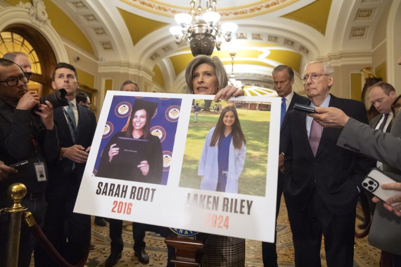 Sen. Joni Ernst, R-Iowa, holds a poster with photos of murder victims Sarah Root and Laken Riley as she speaks speaks after a policy luncheon on Capitol Hill, Tuesday, Feb. 27, 2024, in Washington. (AP Photo/Mark Schiefelbein)