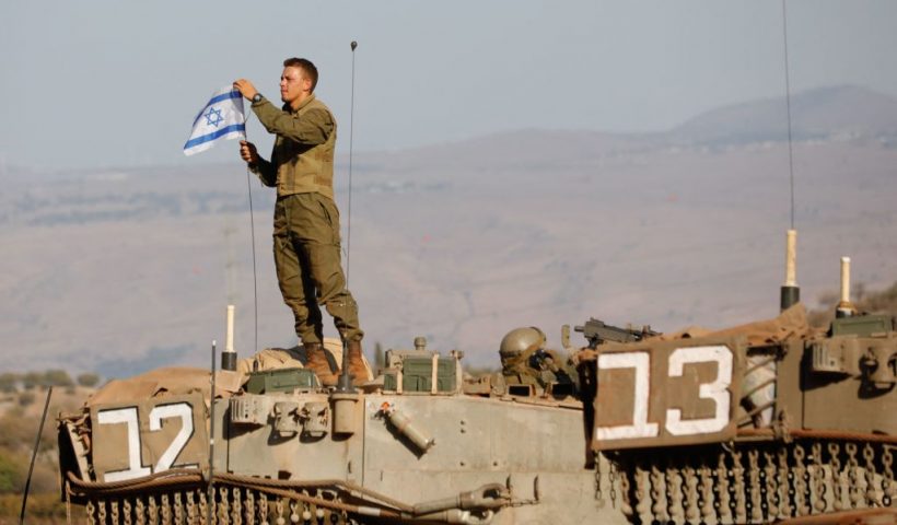 TOPSHOT - An Israeli soldier places a national flag atop a Merkava tank during in a military drill near the border with Lebanon in the upper Galilee region of northern Israel on October 26, 2023, amid the ongoing battles between Israel and the Palestinian group Hamas in the Gaza Strip. (Photo by Jalaa MAREY / AFP) (Photo by JALAA MAREY/AFP via Getty Images)