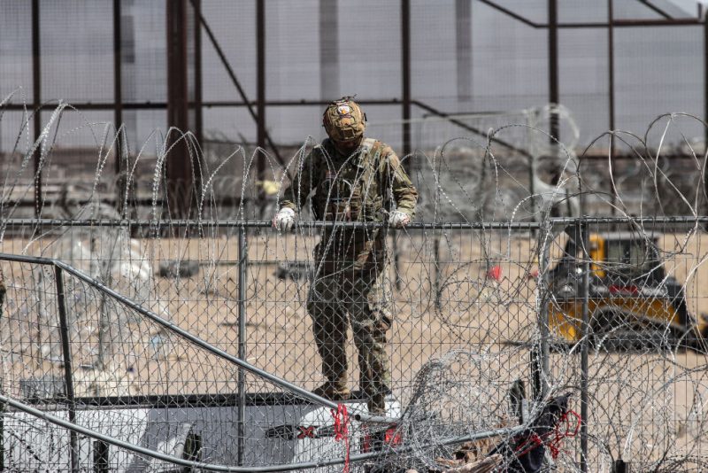 A member of the Texas National Guard reinforces a fence with barbed wire to contain groups of migrant people who try to reach the US side in search of asylum, as seen from Ciudad Juarez, Mexico on March 20, 2024. (Photo by Herika MARTINEZ / AFP) (Photo by HERIKA MARTINEZ/AFP via Getty Images)