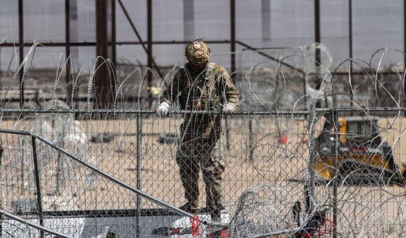 A member of the Texas National Guard reinforces a fence with barbed wire to contain groups of migrant people who try to reach the US side in search of asylum, as seen from Ciudad Juarez, Mexico on March 20, 2024. (Photo by Herika MARTINEZ / AFP) (Photo by HERIKA MARTINEZ/AFP via Getty Images)