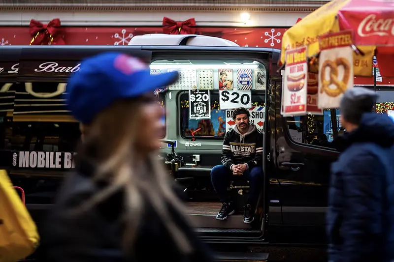An independent barber waits for customers on his van in a local street in New York, U.S., December 25, 2023. REUTERS/Eduardo Munoz/File Photo