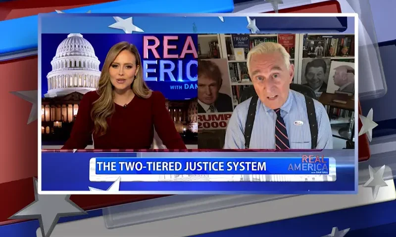Video still from Real America on One America News Network showing a split screen of the host on the left side, and on the right side is the guest, Roger Stone.