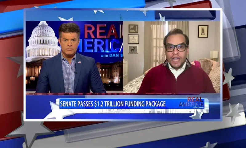 Video still from Real America on One America News Network showing a split screen of the host on the left side, and on the right side is the guest, George Santos.