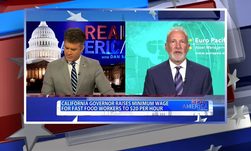 Video still from Real America on One America News Network showing a split screen of the host on the left side, and on the right side is the guest, Peter Schiff.