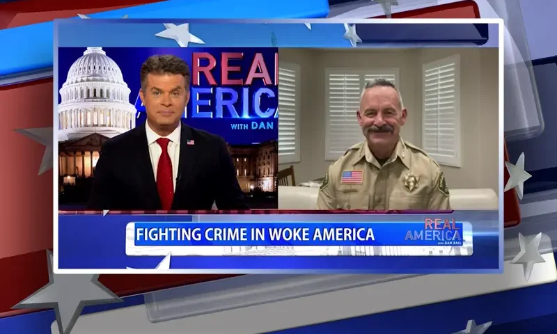 Video still from Real America on One America News Network showing a split screen of the host on the left side, and on the right side is the guest, Chad Bianco.