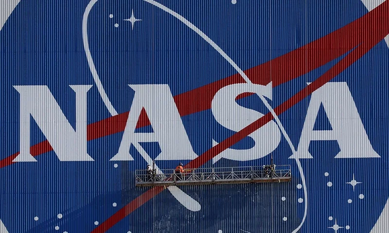 Painters refurbish the NASA logo on the Vehicle Assembly Building at the Kennedy Space Center in Florida in Florida on May 29, 2020. The faded 10-story-tall insignia was last painted 13 years ago. The SpaceX Falcon 9 rocket with the Crew Dragon capsule is rescheduled to launch to the International Space Station on May 30, carrying astronauts Bob Behnken and Doug Hurley. (Photo by Gregg Newton / AFP) (Photo by GREGG NEWTON/AFP via Getty Images)