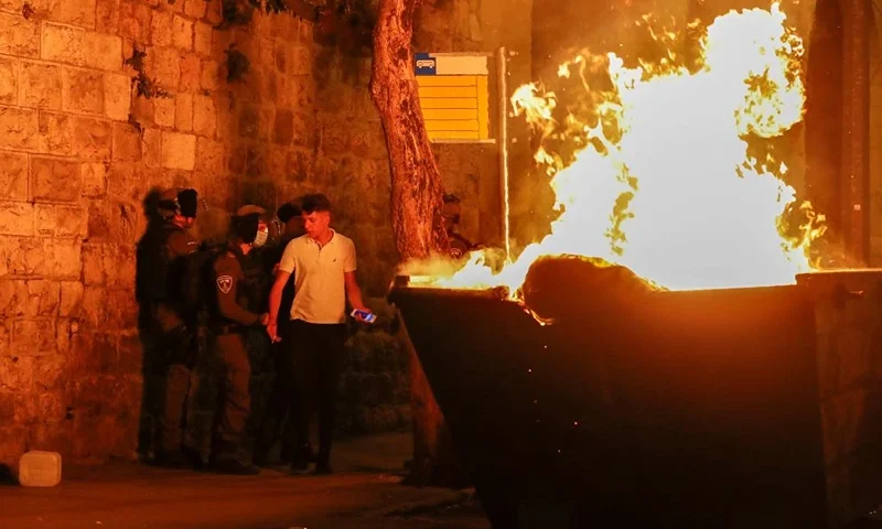 A fire burns in a dumpster as Israeli security forces disperse Palestinian protesters outside the Damascus Gate in Jerusalem's Old City on April 23, 2021, amid mounting tensions over a ban on gatherings and anger fuelled by videos posted of attacks on youths. (Photo by AHMAD GHARABLI / AFP) (Photo by AHMAD GHARABLI/AFP via Getty Images)