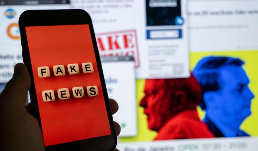 This illustration picture shows a smart phone screen displaying the phrase "Fake News" in front of a desktop screen showing several news and research reports about fake news and disinformation related to the upcoming Brazilian presidential election, in Rio de Janeiro, Brazil, on August 29, 2022. - The sheer volume of fake news, creation of new social media platforms and ever more complex content has made it even more difficult to verify information ahead of the October 2 presidential elections. (Photo by Mauro PIMENTEL / AFP) (Photo by MAURO PIMENTEL/AFP via Getty Images)