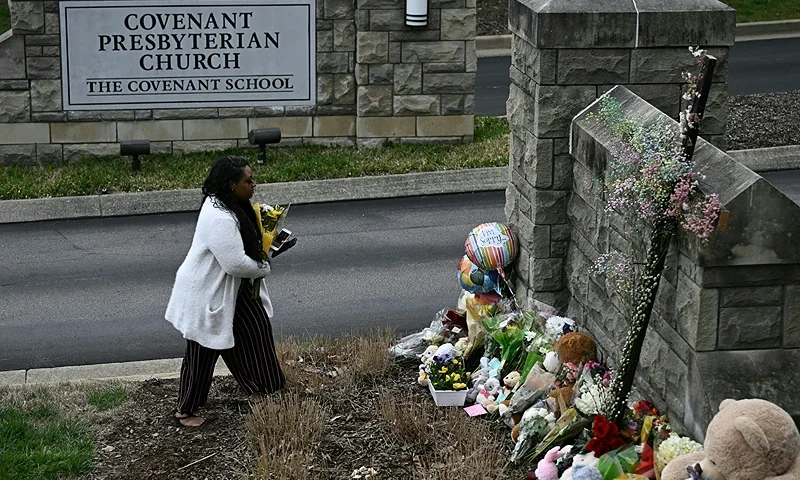 A woman pays her respects at a makeshift memorial for victims outside the Covenant School building at the Covenant Presbyterian Church following a shooting, in Nashville, Tennessee, on March 28, 2023. A heavily armed former student killed three young children and three staff in what appeared to be a carefully planned attack at a private elementary school in Nashville on March 27, before being shot dead by police. Chief of Police John Drake named the suspect as Audrey Hale, 28, who the officer later said identified as transgender. (Photo by Brendan SMIALOWSKI / AFP) (Photo by BRENDAN SMIALOWSKI/AFP via Getty Images)