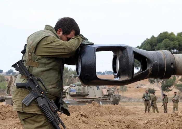 TOPSHOT - An Israeli soldier rests his head on the gun barrel of a self-propelled artillery howitzer as Israeli soldiers take positions near the border with Gaza in southern Israel on October 9, 2023. One month after Israel was wracked by Hamas attacks, life has been upended for both the Palestinians and Israel after it launched a war of reprisal in the Gaza Strip. The October 7 attacks by Hamas militants who stormed across from Gaza and struck kibbutzim and southern Israeli areas killed 1,400 people, mostly civilians, and deeply scarred the nation. The health ministry in Hamas-run Gaza says nearly 9,500 have been killed, two-thirds of them women and children, and mostly civilians. (Photo by JACK GUEZ / AFP) (Photo by JACK GUEZ/AFP via Getty Images)