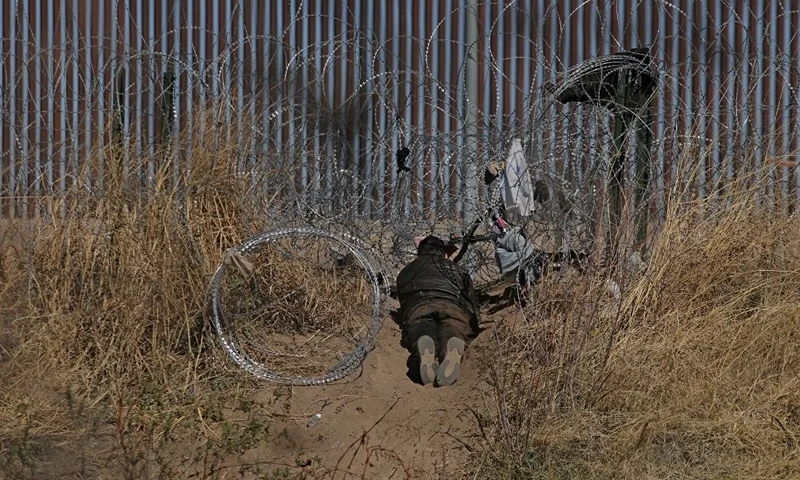 A migrant tries to cut a barbed wire fence installed to prevent the entry of illegal migrants across the Rio Bravo/Grande from Ciudad Juarez, state of Chihuahua, Mexico on February 12, 2024. (Photo by Herika Martinez / AFP) (Photo by HERIKA MARTINEZ/AFP via Getty Images)
