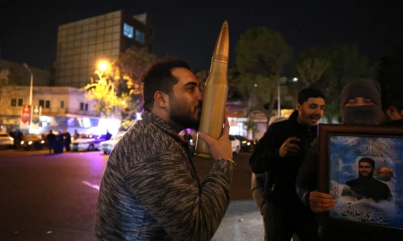 IRAN-ISRAEL-PALESTINIAN-CONFLICT A demonstrator kisses a bullet shell replica as others gather at Palestine Square in Tehran on April 14, 2024, after Iran launched a drone and missile attack on Israel. Iran's Revolutionary Guards confirmed early April 14, 2024 that a drone and missile attack was under way against Israel in retaliation for a deadly April 1 drone strike on its Damascus consulate. (Photo by ATTA KENARE / AFP) (Photo by ATTA KENARE/AFP via Getty Images)