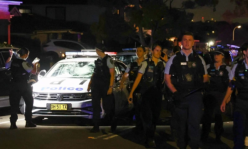 New South Wales police walk past a damaged police car after a mob was pushed back outside the Christ the Good Shepherd Church in Sydney's western suburb of Wakeley on April 15, 2024, after several people were stabbed in the church premises. Australian police arrested a man after several people were stabbed at a church in Sydney on April 15 and emergency services said four people were being treated for non-life threatening injuries. (Photo by DAVID GRAY / AFP) (Photo by DAVID GRAY/AFP via Getty Images)