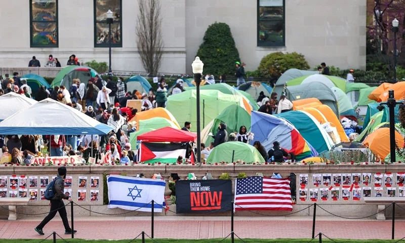 TOPSHOT - A man walks past Israeli and US flags alongside portraits of Israelis taken hostage by the militant Palestinian group Hamas in front of the pro-Palestinian encampment at Columbia University in New York on April 23, 2024. US President Joe Biden condemned any anti-Semitism on college campuses April April 21, 2024 as pro-Palestinian protesters at Columbia University spent their fifth day demanding the school sever financial ties with key US ally Israel. (Photo by Charly TRIBALLEAU / AFP) (Photo by CHARLY TRIBALLEAU/AFP via Getty Images)