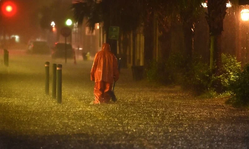 TOPSHOT - A communal worker walks at a flooded street in downtown Charleston, SC on October 03, 2015. Much of the US southeast was under water Saturday, deluged by rains from Hurricane Joaquin, with forecasters predicting more historic flooding in coming days for the already waterlogged region. AFP PHOTO/MLADEN ANTONOV (Photo by MLADEN ANTONOV / AFP) (Photo by MLADEN ANTONOV/AFP via Getty Images)