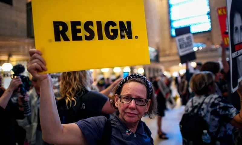 A protester displays a placard calling on US President Donald Trump to resign during Rise and Resist Against White Supremacy demonstration inside the Grand Central Station in New York on September 18, 2017. US President Donald Trump will deliver his maiden address on Day One of the 72nd session of United Nations General Assembly on September 19, 2017. / AFP PHOTO / Jewel SAMAD (Photo credit should read JEWEL SAMAD/AFP via Getty Images)