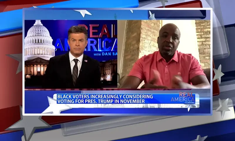 Video still from Real America on One America News Network showing a split screen of the host on the left side, and on the right side is the guest, Mark 'King' Carter.