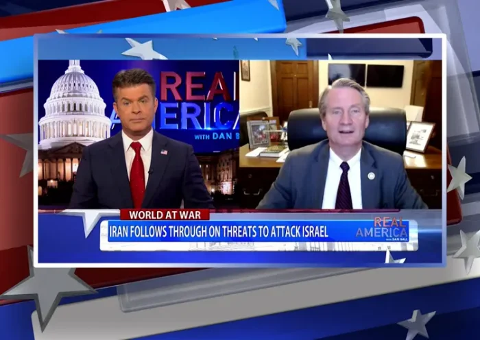 Video still from Real America on One America News Network showing a split screen of the host on the left side, and on the right side is the guest, Tim Burchett.