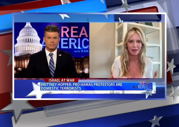 Video still from Real America on One America News Network showing a split screen of the host on the left side, and on the right side is the guest, Brittney Hopper.
