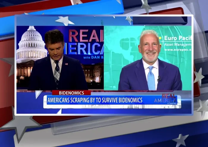 Video still from Real America on One America News Network showing a split screen of the host on the left side, and on the right side is the guest, Peter Schiff.
