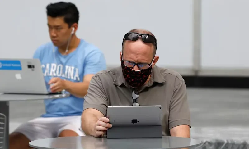 People use an Apple laptop computer and an Apple iPad in Manhattan, New York City, U.S., August 25, 2020. REUTERS/Andrew Kelly/File Photo