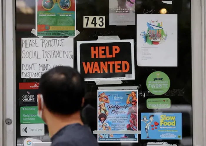 A pedestrian passes a "Help Wanted" sign in the door of a hardware store in Cambridge, Massachusetts, U.S., July 8, 2022. REUTERS/Brian Snyder/File Photo