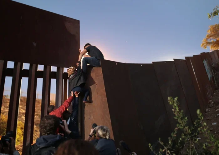 TIJUANA, MEXICO - DECEMBER 03: Members of the migrant caravan climb over the U.S.-Mexico border fence on December 3, 2018 while crossing into San Diego, CA from Tijuana, Mexico. Many had planned to request political asylum in the United States after traveling more than 6 weeks from Central America. (Photo by John Moore/Getty Images)