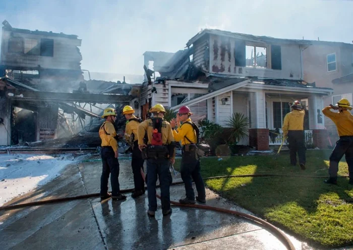 Firefighters hose down a burning house during the Tick Fire in Agua Dulce near Santa Clarita, California on October 25, 2019. - California firefighters battled through the night to contain a fast-moving wildfire driven by high winds that was threatening to engulf thousands of buildings. Around 40,000 people were told to flee the Tick Fire, which was raging across 4,000 acres (1,600 hectares) just north of Los Angeles. (Photo by Mark RALSTON / AFP) (Photo by MARK RALSTON/AFP via Getty Images)