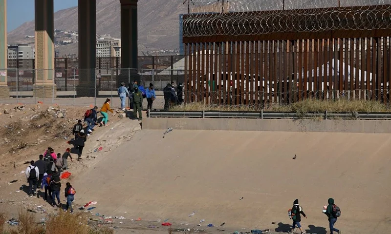 Migrants wait in line to be processed by the Border Patrol along the border wall after crossing the Rio Grande river into El Paso, Texas on the US-Mexico border as seen from Ciudad Juarez, Chihuahua state, Mexico on December 19, 2022. - The US Supreme Court halted December 19, 2022 the imminent removal of Title 42, a key policy used since the administration of president Donald Trump to block migrants at the southwest border, amid worries over a surge in undocumented immigrants. (Photo by HERIKA MARTINEZ / AFP) (Photo by HERIKA MARTINEZ/AFP via Getty Images)