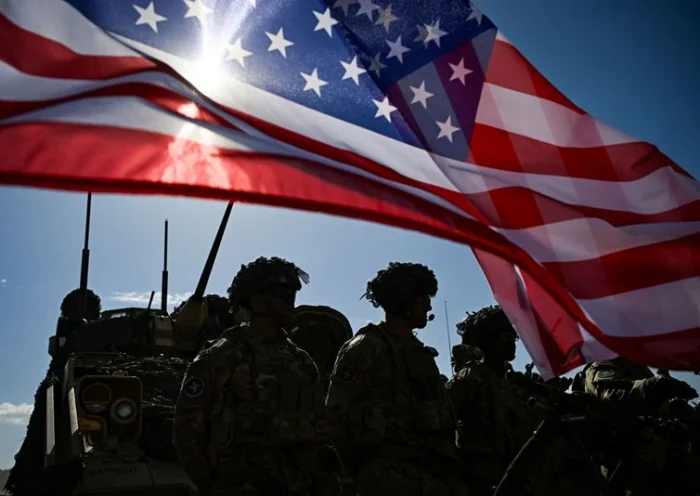 US Army soldiers stand in formation next to a US flag and a US Army armoured vehicle as they take part in the NATO "Noble Blueprint 23" joint military exercise at the Novo Selo military ground, northwestern Bulgaria, on September 26, 2023. More than two hundred soldiers from Bulgaria, Italy, USA, Greece, North Macedonia, Albania, Montenegro and Turkey are taking part in the exercise to demonstrate operational capabilities during the NATO "Noble Blueprint 23" joint exercise. (Photo by Nikolay DOYCHINOV / AFP) (Photo by NIKOLAY DOYCHINOV/AFP via Getty Images)