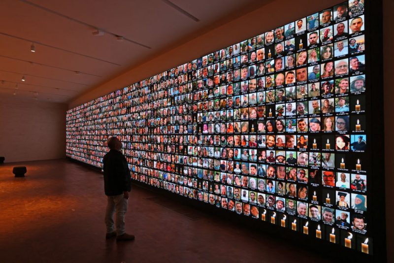 TOPSHOT - A visitor looks at a giant backlight screen bearing the portraits of the Israeli people who were killed during the October 7 attacks by Hamas in southern Israel or those who died during the ongoing battles between Israel and the Palestinian militant group Hamas in Gaza, at the National Library in Jerusalem, on January 25, 2024. (Photo by AHMAD GHARABLI / AFP) (Photo by AHMAD GHARABLI/AFP via Getty Images)