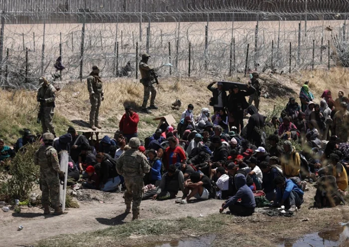 Migrants of different nationalities pray in front of anti-riot agents of the Texas National Guard who prevent passage towards their border line, as seen from Ciudad Juarez, state of Chihuahua, Mexico, on April 16, 2024. (Photo by Herika Martinez / AFP) (Photo by HERIKA MARTINEZ/AFP via Getty Images)