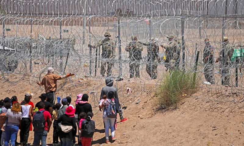 Migrants seeking to enter the United States through a barbed wire fence installed along the Rio Grande are driven away with pepper spray shots by Texas National Guard agents at the border with Ciudad Juarez, Chihuahua State, Mexico, on May 13, 2024. (Photo by HERIKA MARTINEZ / AFP) (Photo by HERIKA MARTINEZ/AFP via Getty Images)