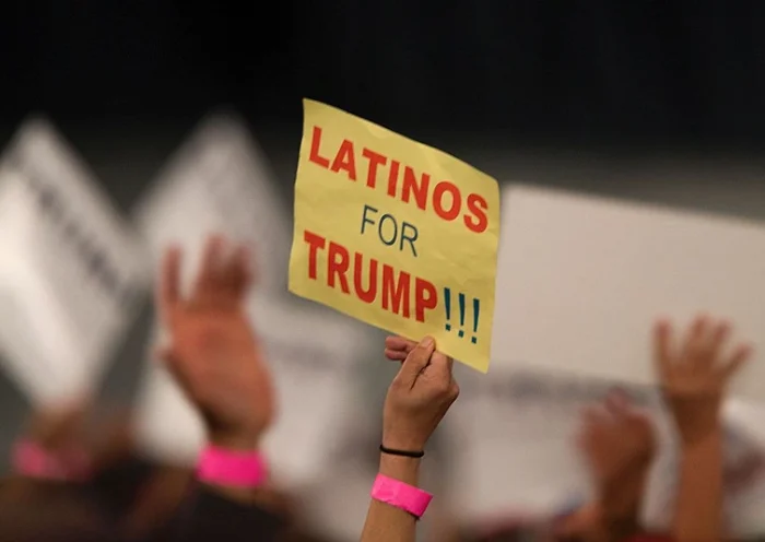 A woman hoods a sign expressing Latino support for Republican presidential candidate Donald Trump at his campaign rally at the Orange County Fair and Event Center, April 28, 2016, in Costa Mesa, California. Trump is vying for votes in the June 7 California primary election in hope of narrowing the gap to the 1,237 delegates needed to win the Republican presidential nomination. / AFP / DAVID MCNEW (Photo credit should read DAVID MCNEW/AFP via Getty Images)