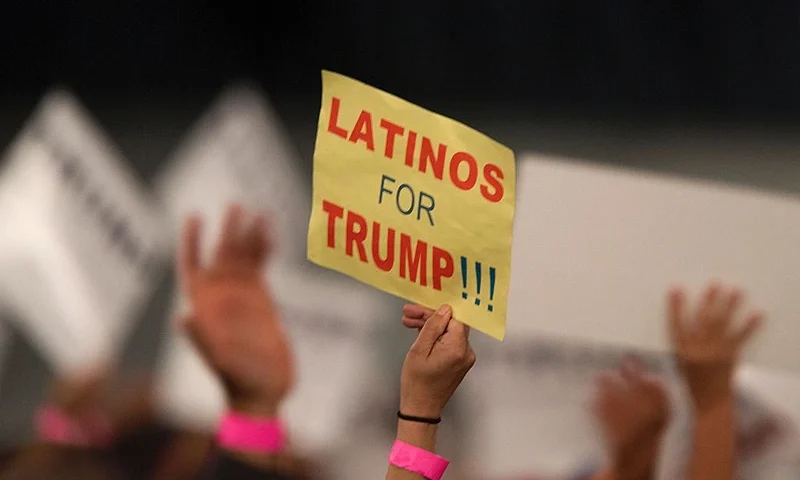 A woman hoods a sign expressing Latino support for Republican presidential candidate Donald Trump at his campaign rally at the Orange County Fair and Event Center, April 28, 2016, in Costa Mesa, California. Trump is vying for votes in the June 7 California primary election in hope of narrowing the gap to the 1,237 delegates needed to win the Republican presidential nomination. / AFP / DAVID MCNEW (Photo credit should read DAVID MCNEW/AFP via Getty Images)