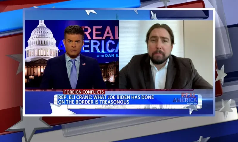 Video still from Real America on One America News Network showing a split screen of the host on the left side, and on the right side is the guest, Rep. Eli Crane.