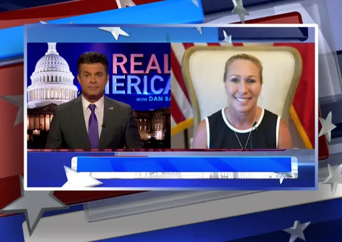 Video still from Real America on One America News Network showing a split screen of the host on the left side, and on the right side is the guest, Rep. Marjorie Taylor Greene.