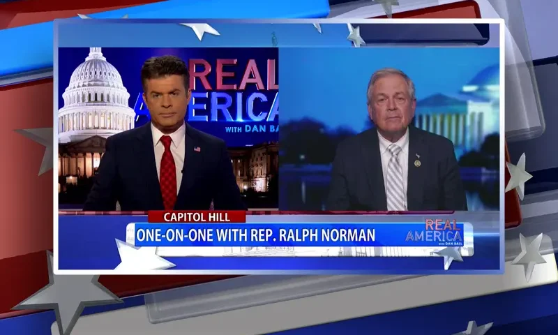 Video still from Real America on One America News Network showing a split screen of the host on the left side, and on the right side is the guest, Rep. Ralph Norman.